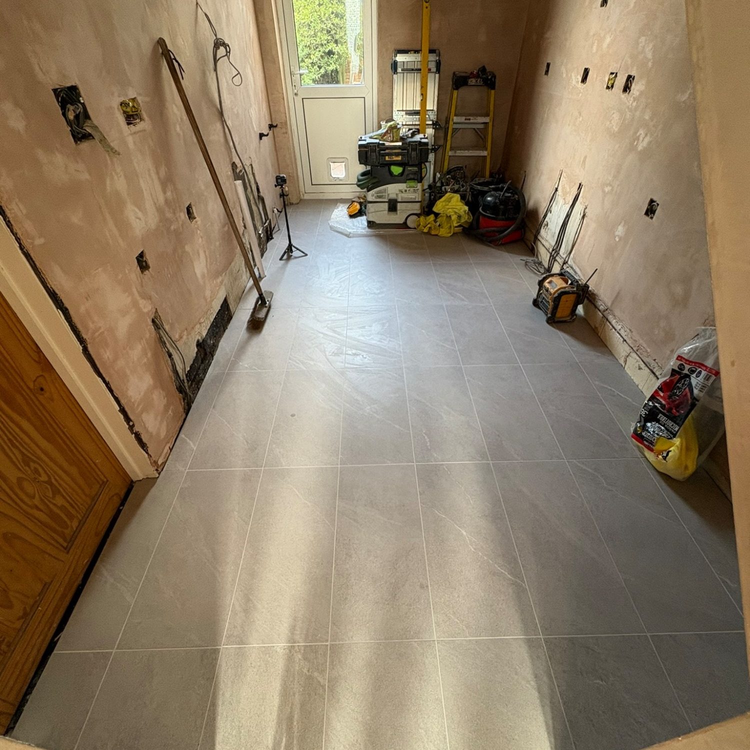 Brislington kitchen during renovation with freshly plastered walls and a new tiled floor