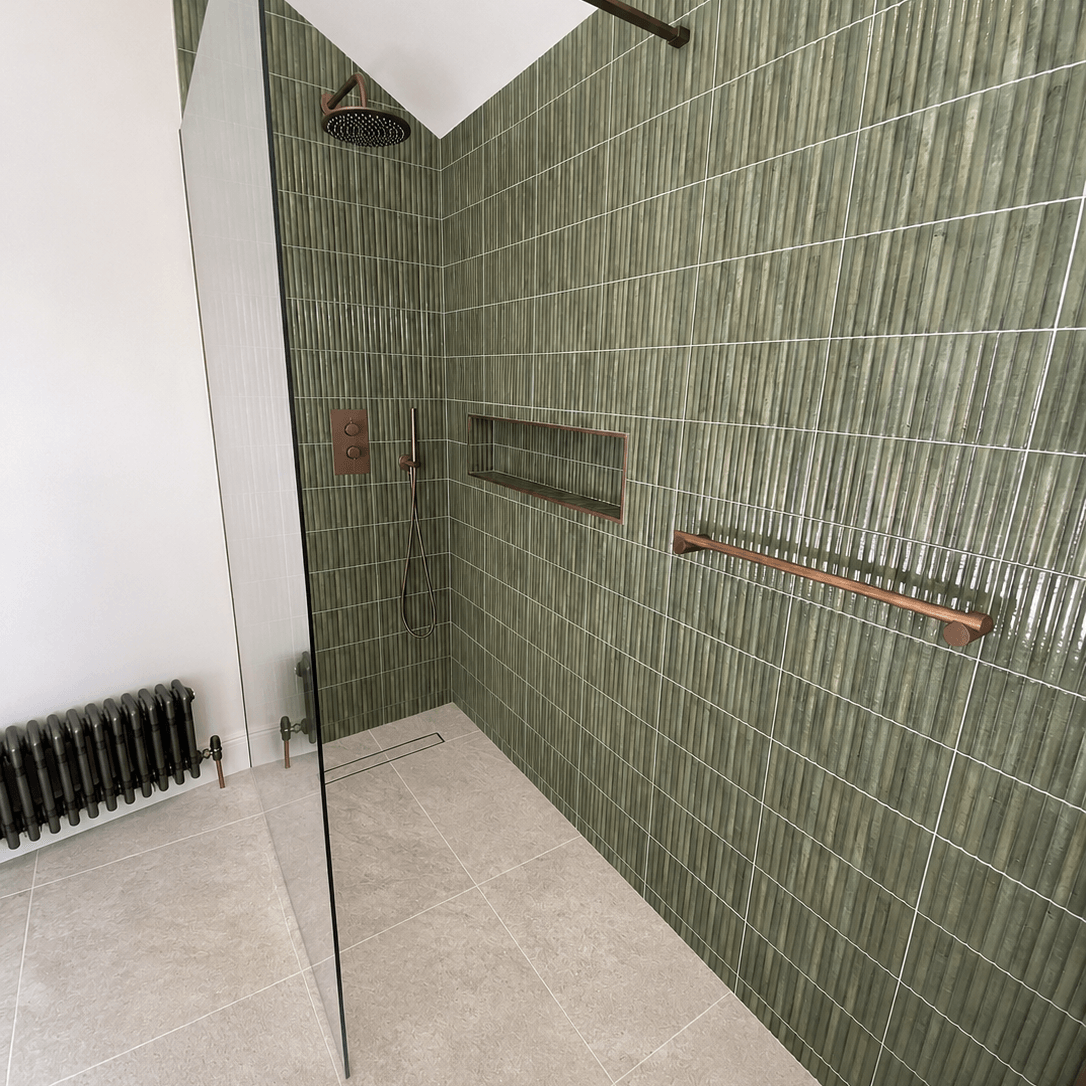 Green tiled shower wall with recessed storage niche and glass screen in Southville
