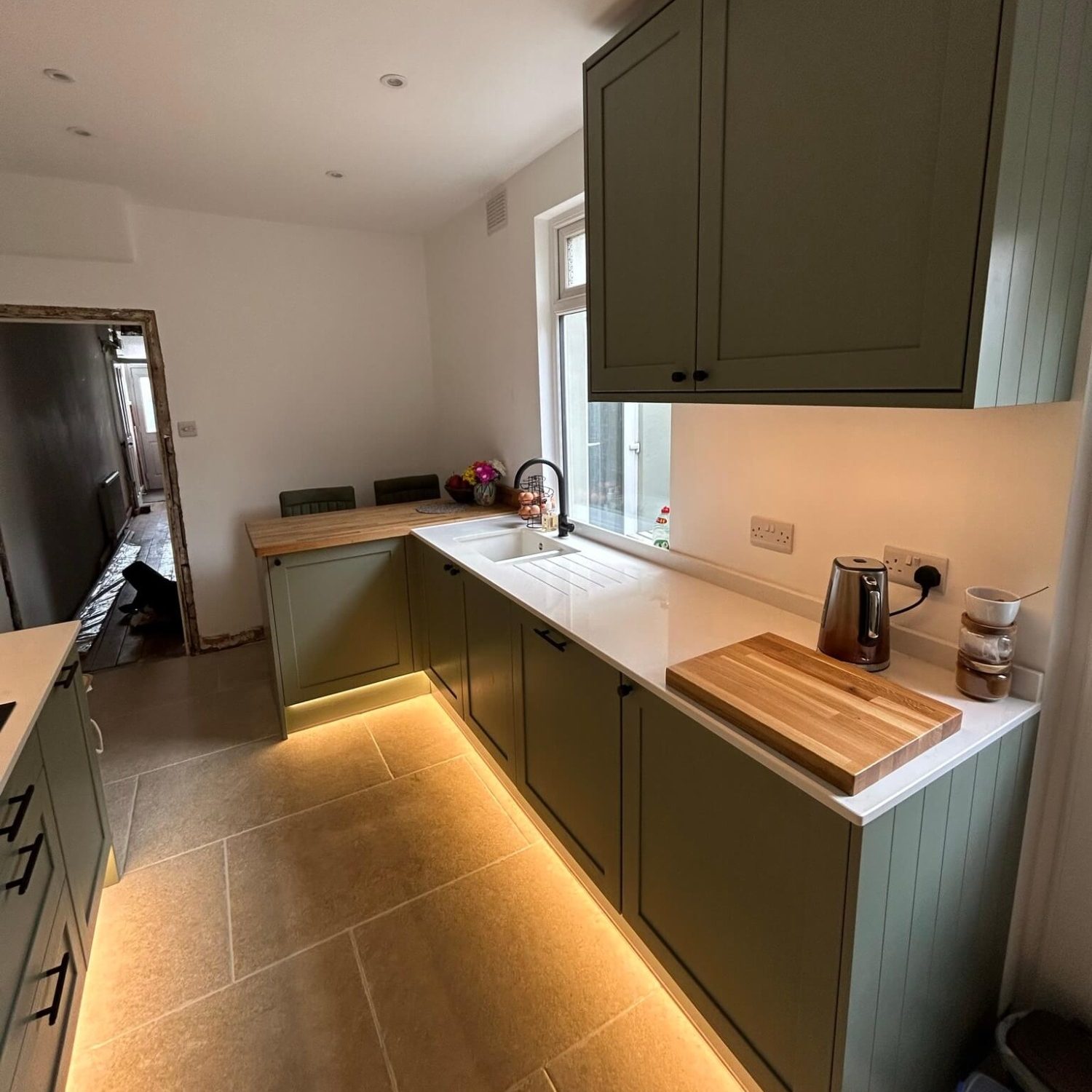 Green fitted kitchen cabinets, wood worktops and under-cabinet lighting in Bedminster