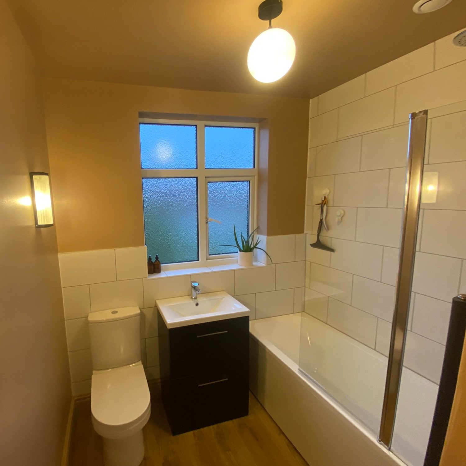 Renovated Brislington bathroom with bath, dark vanity unit and toilet beneath a window