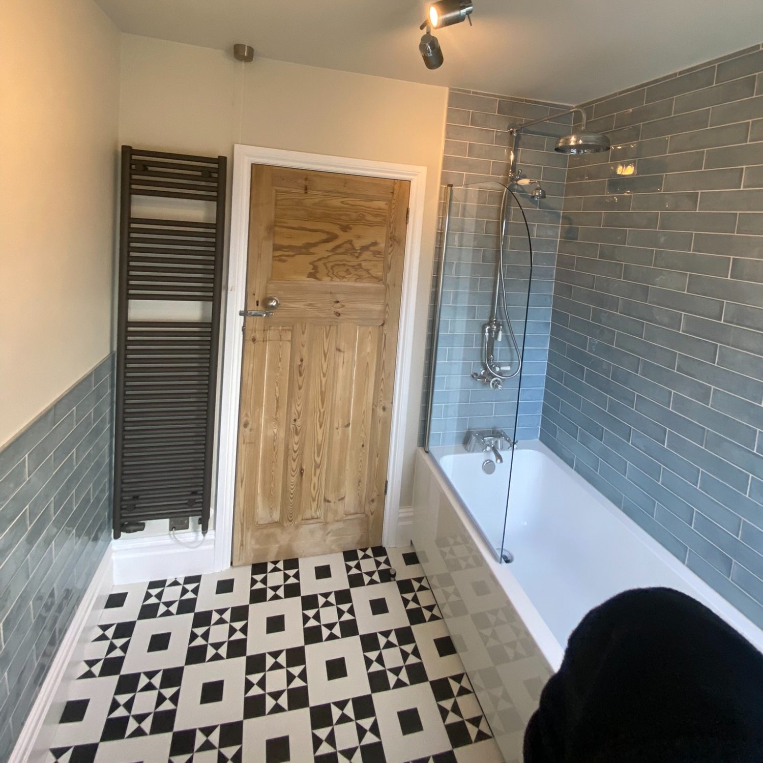 Brislington bathroom with grey wall tiles, bath, black towel radiator and patterned floor
